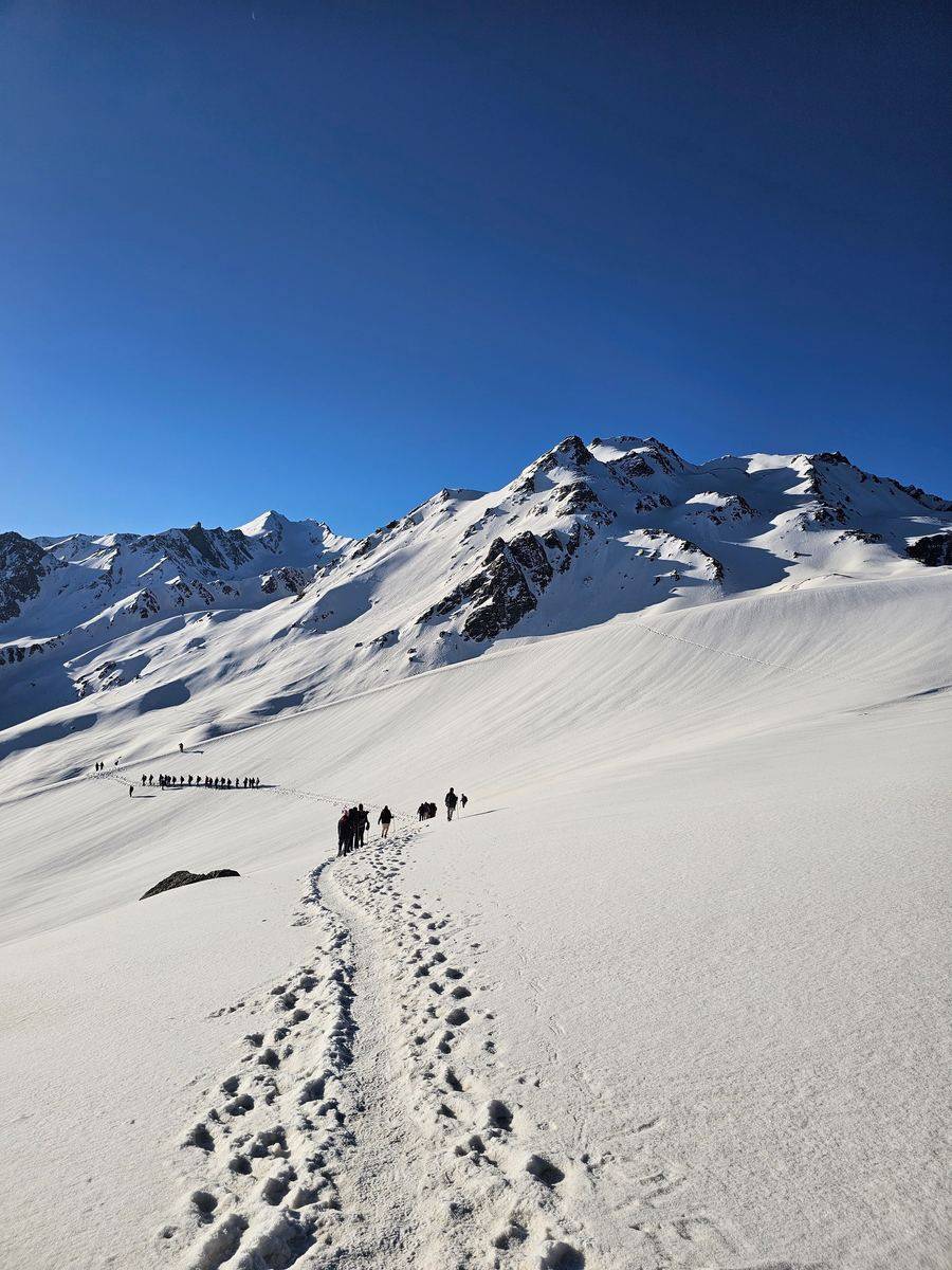 Trekkers climbing a snow slope towards a Himalayan pass